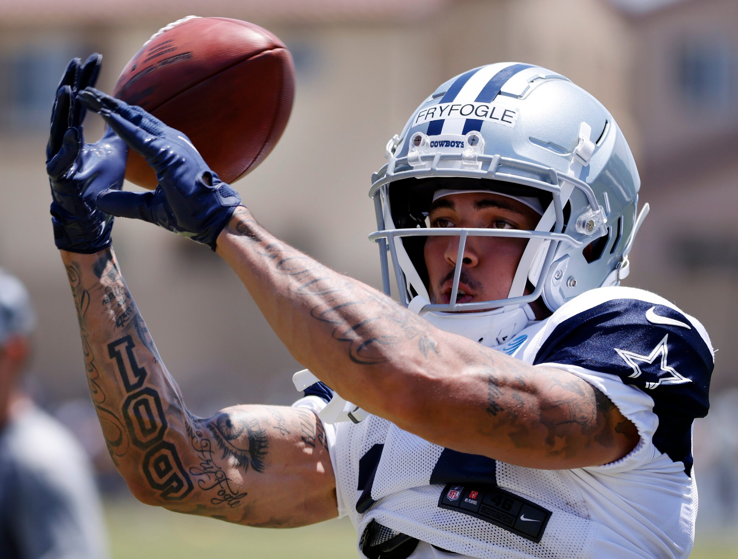 Dallas Cowboys wide receiver Ty Fryfogle (14) lets a machine driven pass slip past his...