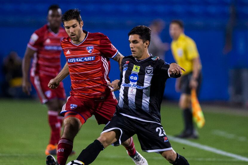 FC Dallas midfielder Ryan Hollingshead (12) defends Tauro F.C.'s Jose Tamburelli (23) during...
