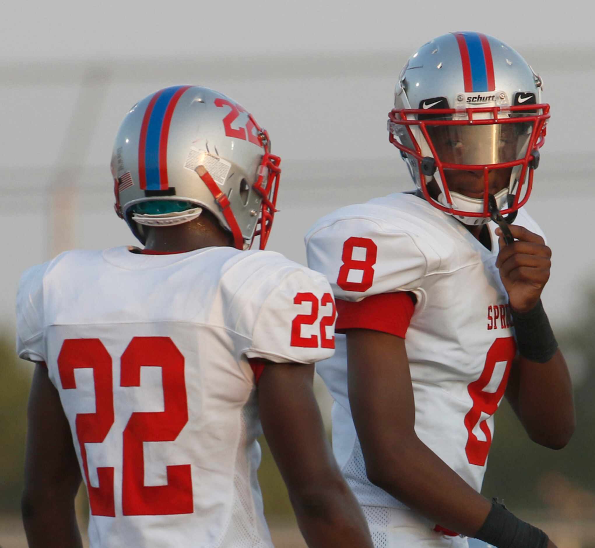 Spruce quarterback Damethis Davis (8) glances back toward running back Shawn Hodge (22)...