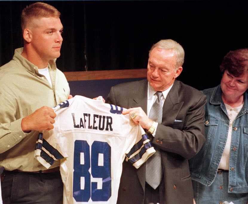 Dallas Cowboys owner Jerry Jones, center, helps the Cowboys' first draft pick, Louisiana...
