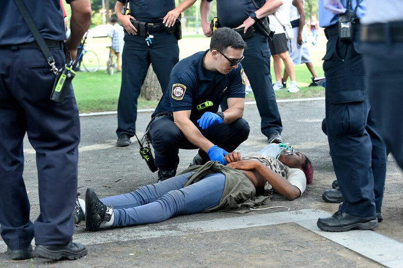 A medical responder checks the pulse of a woman who was found unconscious with a companion...