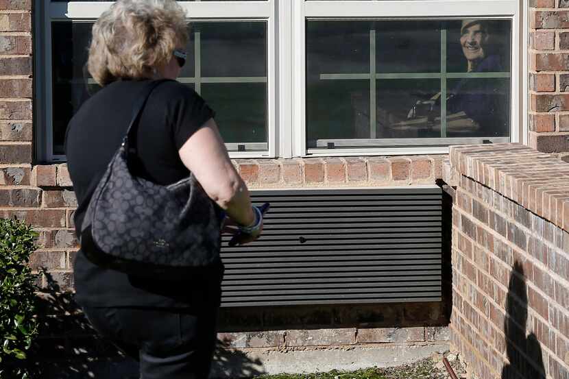 Cindy Goleman walks up to the window of her mother Peggy White from outside the window at...