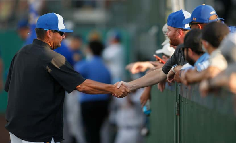 Corsicana head coach Heath Autrey greets a fan on his way to the third base coach's box to...