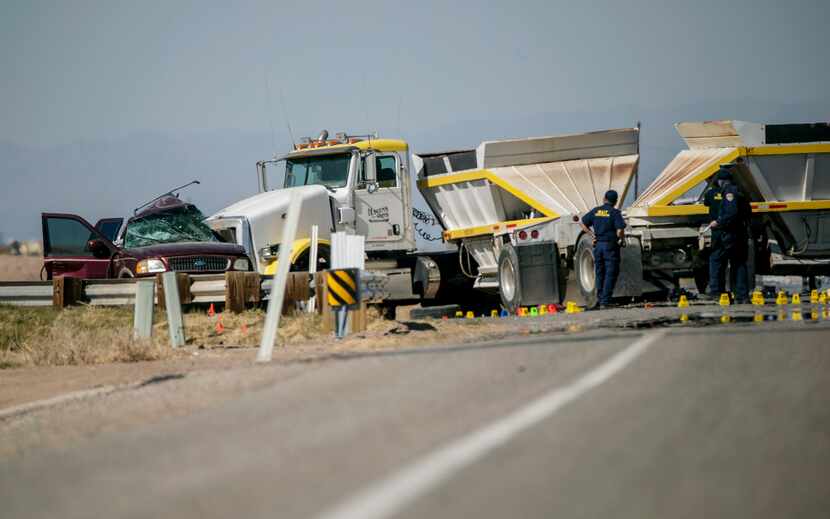 Police investigate the scene where an SUV carrying 25 people collided with a semi-truck,...