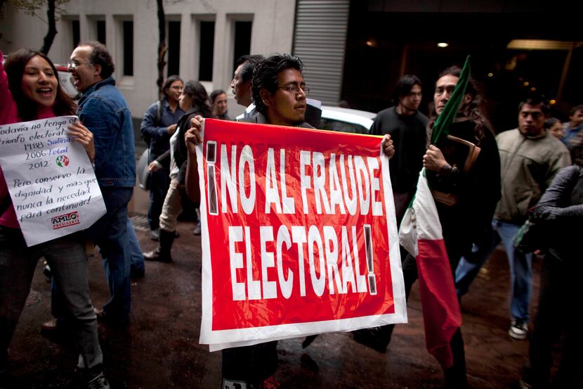 A man holds up a sign that reads "No to electoral fraud" outside a hotel where Mexican...