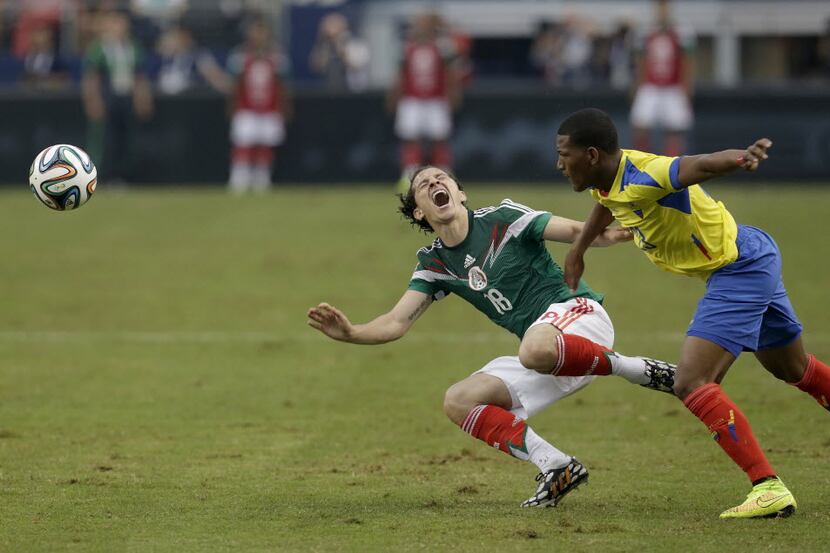 Mexico's Andres Guardado (18) goes down after colliding with Ecuador's Carlos Gruezo (23) in...