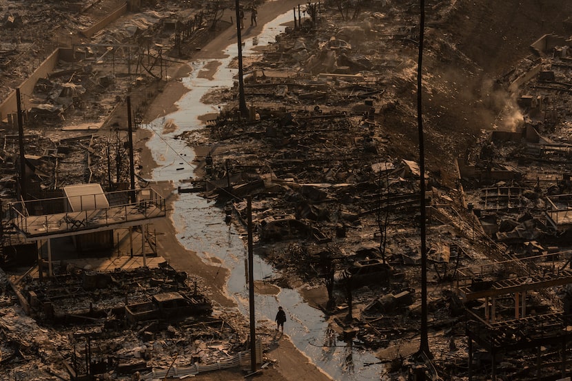 A person walks amid the destruction left behind by the Palisades Fire in the Pacific...