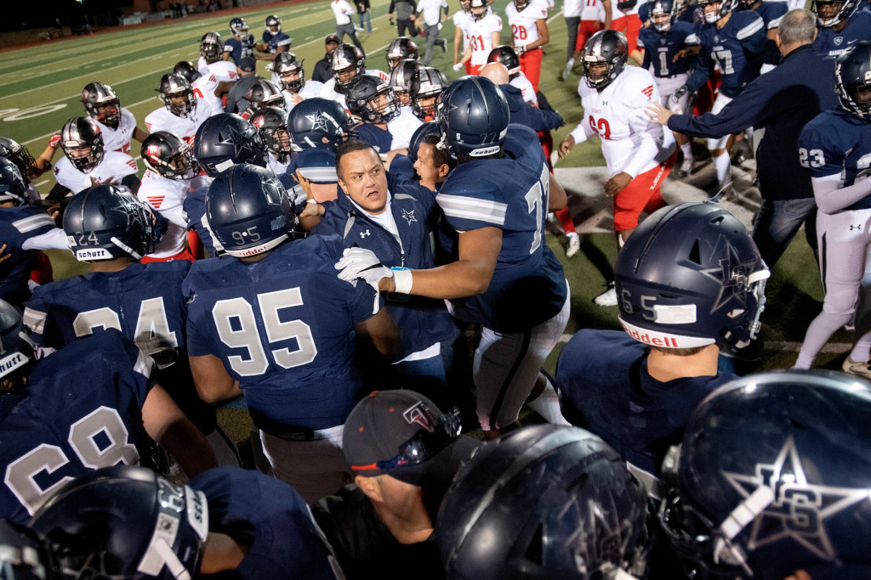 Frisco Lone Star assistant coach Lorenzo pool ushers junior linebacker Jaylan Ford (24) back...