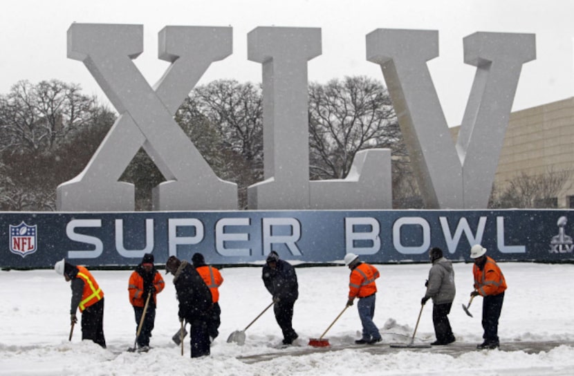 Workers try to clear a sidewalk near the Dallas Convention Center after a morning snow storm...