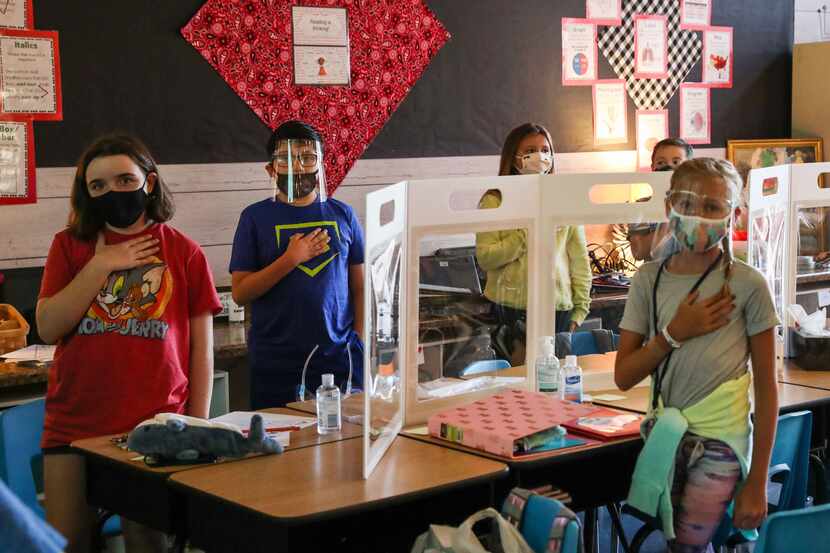 4th grade students wearing masks and face covers, take the pledge of allegiance at Jacobs...