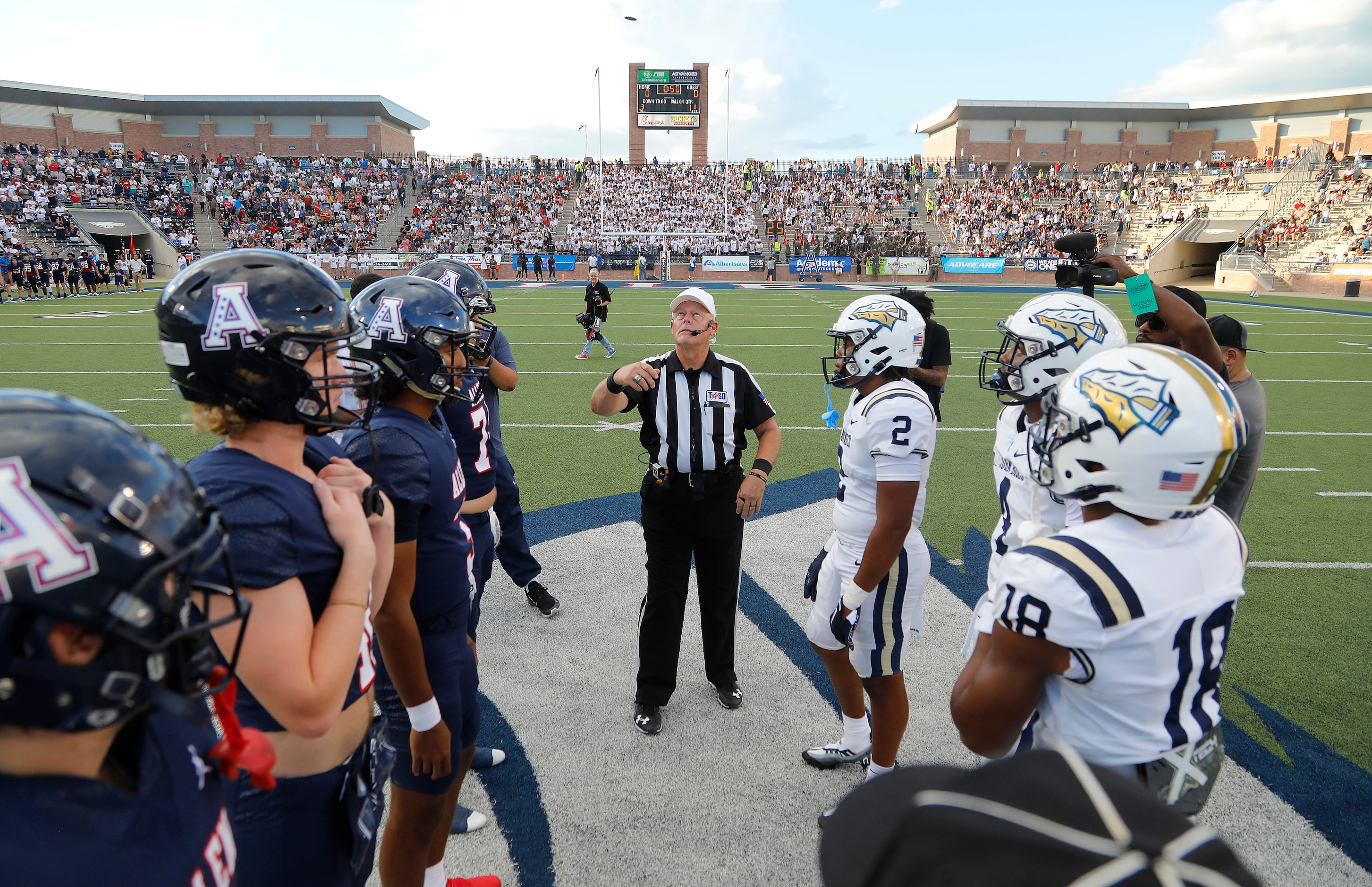 Captains for both teams meet with officials at midfield for the coin toss before kickoff as...