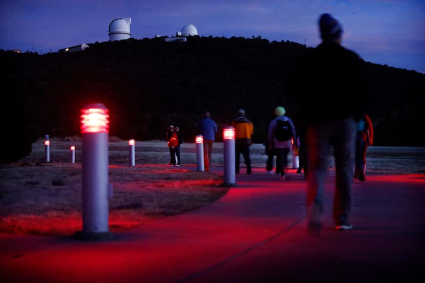 Visitors walk along the red-lighted walkway to a Star Party at the University of Texas's...