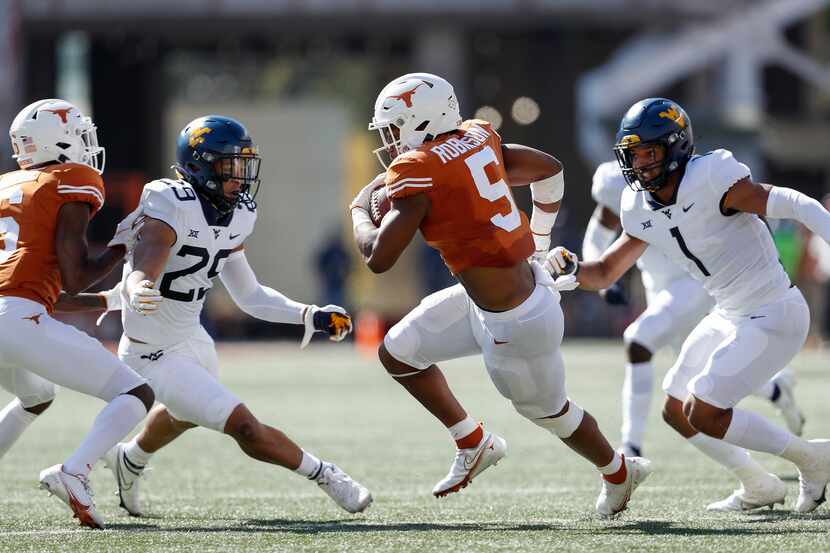 Texas running back Bijan Robinson (5) runs the ball while defended by West Virginia...