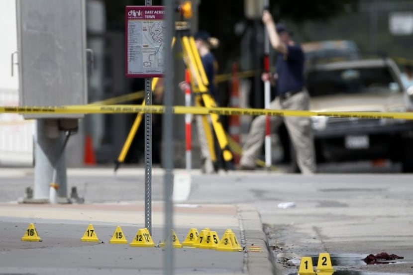  Evidence markers on seen on a sidewalk in front of Dallas police headquarters as members of...