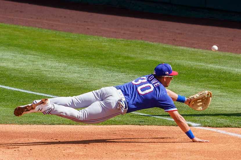 El primera base de los Rangers de Texas, Nate Lowe, se lanza al aire para tratar de detener...