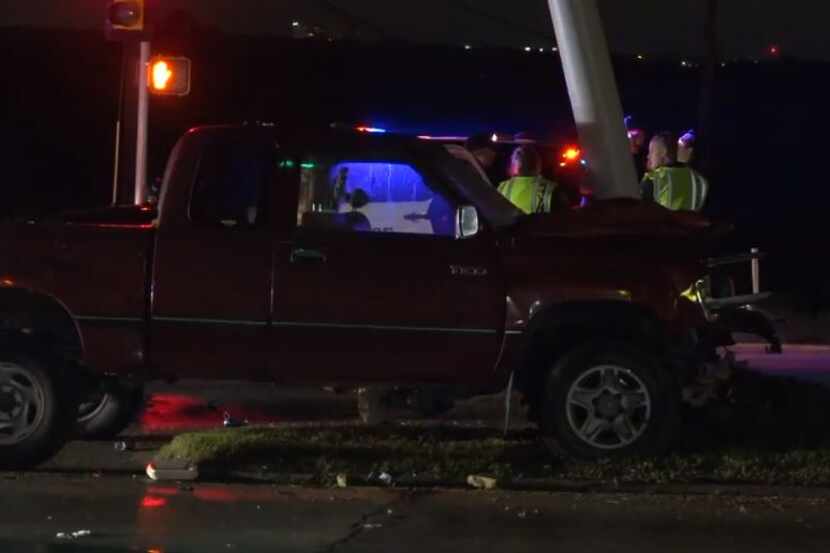 Fort Worth police examine the wreckage of a truck that hit a traffic light pole Wednesday...