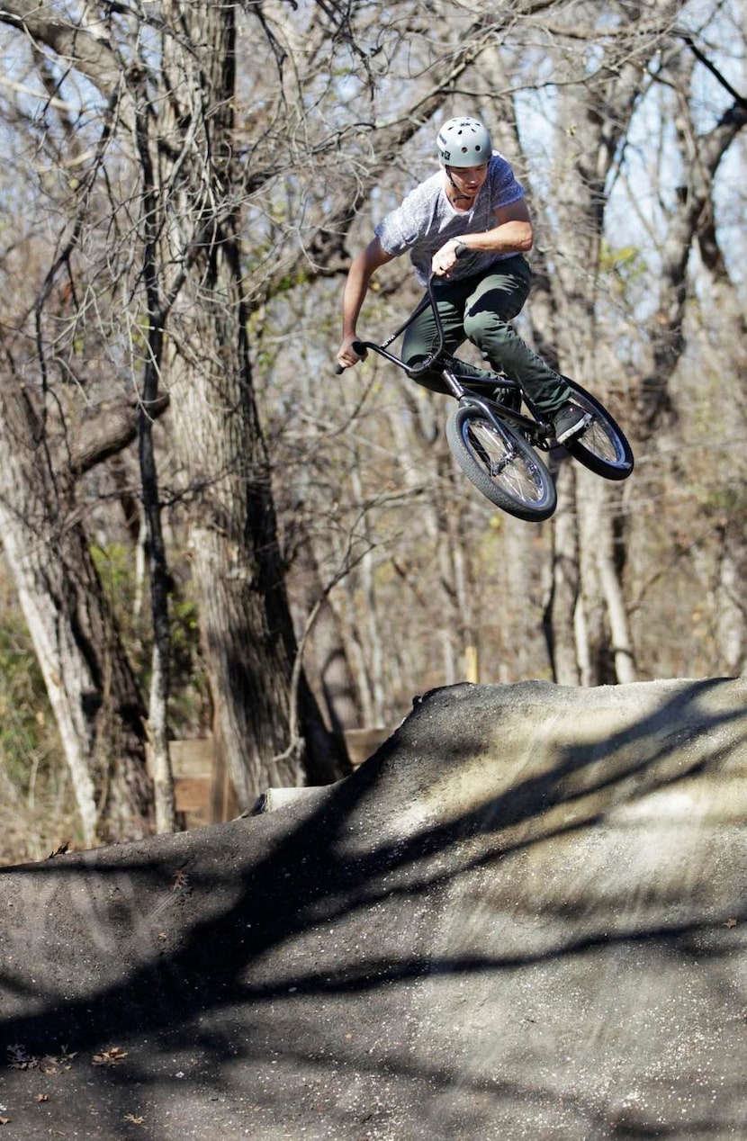 
Assistant trail steward Kevin Stasun soars off a jump at The Woods. Riders move through a...