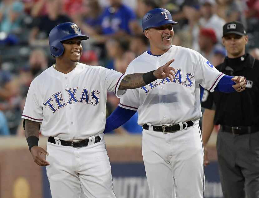 Texas Rangers first base coach Hector Ortiz teaches rookie outfielder Willie Calhoun, left,...