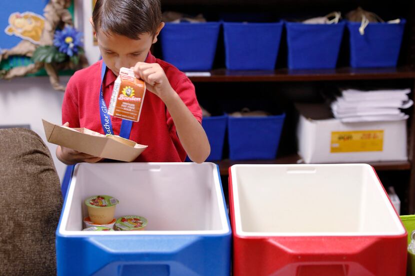 Jeremiah Busbey, 7, gathers his breakfast in his classroom at Heather Glen Elementary School...