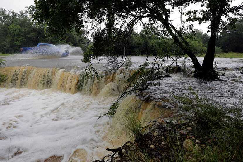 A motorist passes through a low-water crossing Tuesday near New Braunfels. (Eric Gay/The...