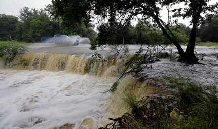 A motorist passes through a low-water crossing Tuesday near New Braunfels. (Eric Gay/The...