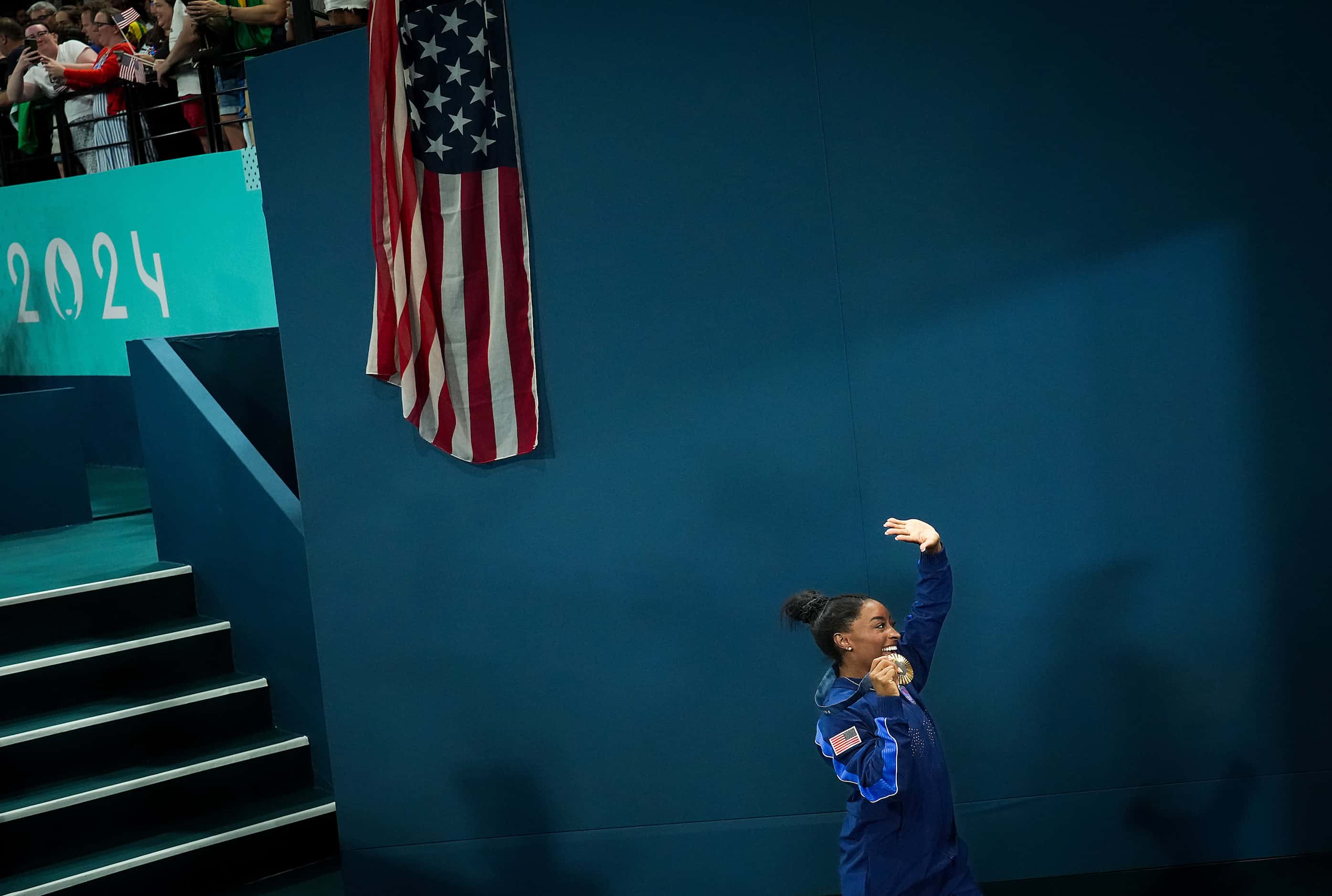 Simone Biles of the United States waves to the crowd as she leaves the floor after winning...