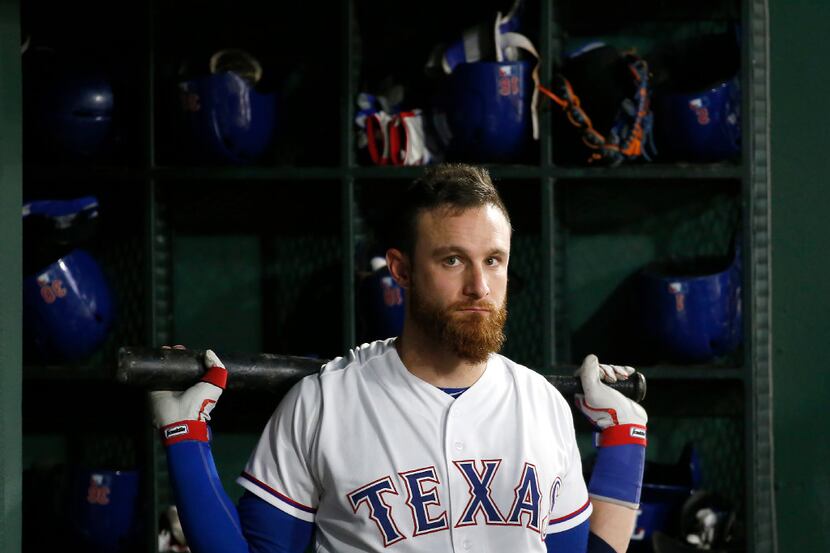 Texas Rangers catcher Jonathan Lucroy gets ready in the dugout during the first inning...