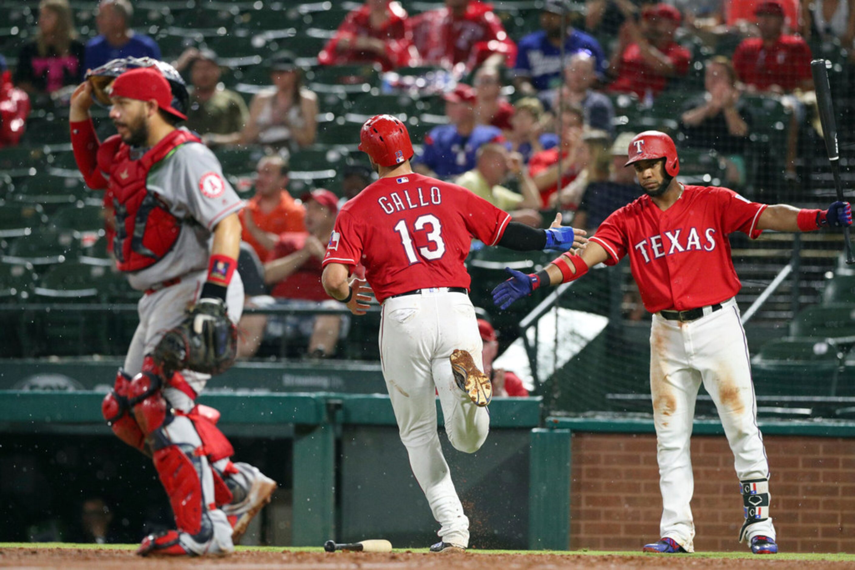 Texas Rangers' Joey Gallo (13) is greeted by Elvis Andrus (1) after scoring in the fourth...