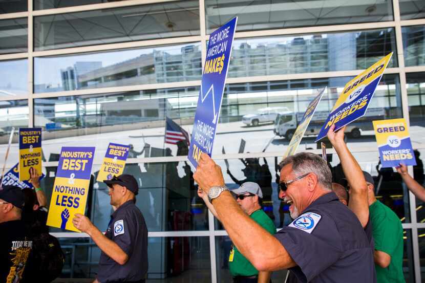 American Airlines employees protest the lack of a new contract for baggage carriers,...