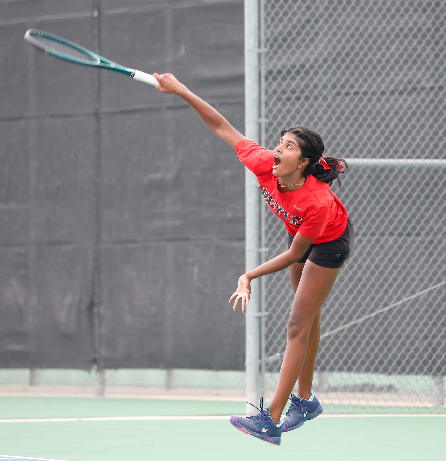 Argyle's Meghna Arun Kumar follows through on a serve in a 5A girls singles match where she...