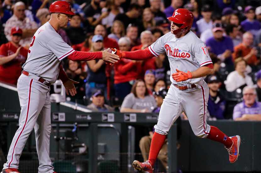 Philadelphia Phillies' Rhys Hoskins is congratulated by third base coach Dusty Wathan as he...