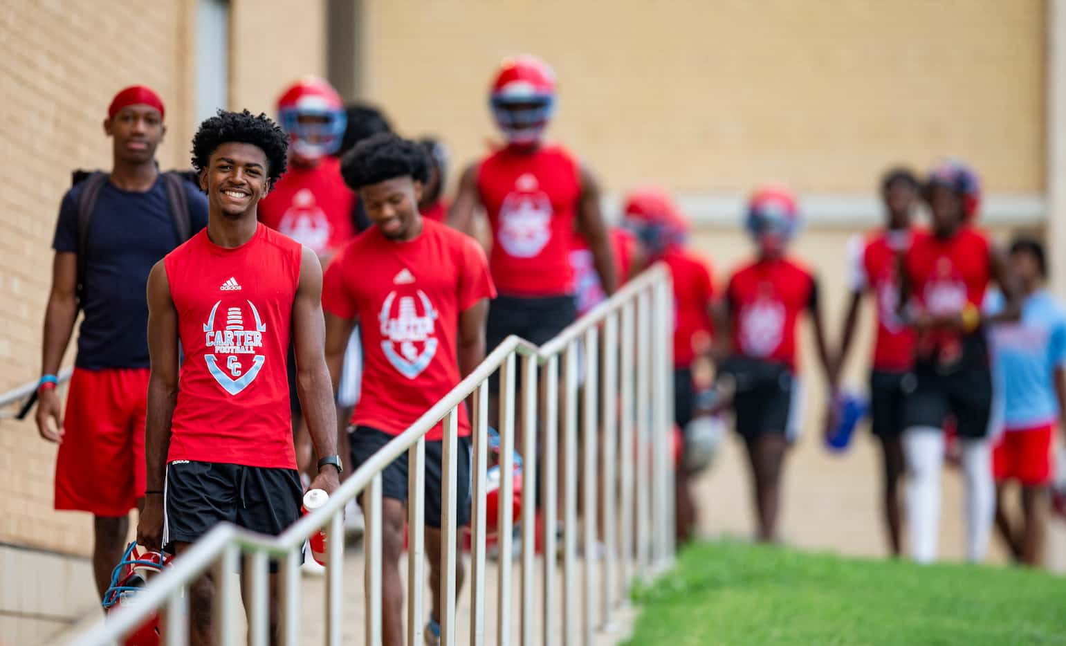Carter senior quarterback William Young, left, leads his team to the practice field for the...