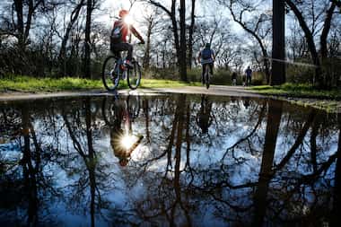 After a rainy period, cyclists and walkers navigated the water puddles along the paths of...