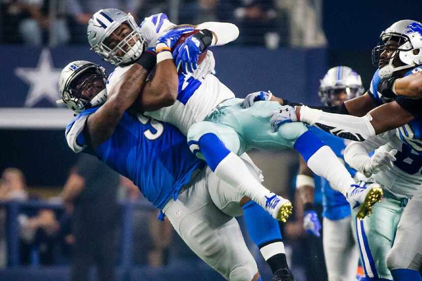Dallas Cowboys running back Ezekiel Elliott (21) is slammed down by Detroit Lions defensive...