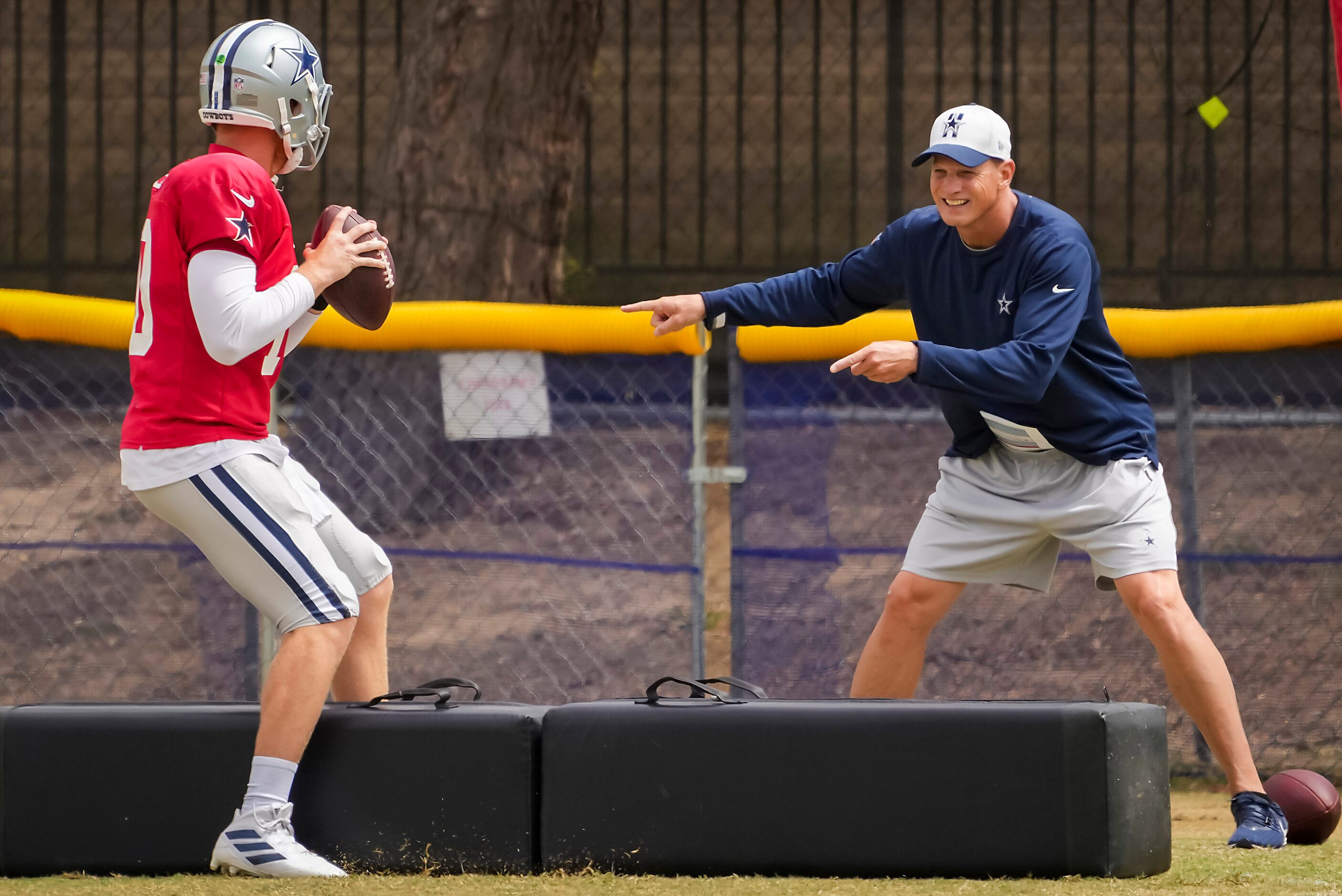 Dallas Cowboys quarterback Cooper Rush (10) runs a drill under the direction of quarterbacks...