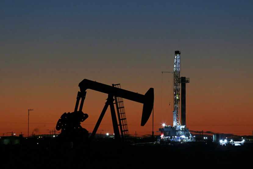 In this Oct. 9, 2018, photo, an oil rig and pump jack work along the roadside of FM 1788 in...