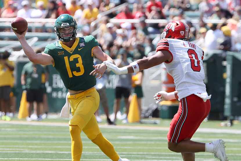 Baylor quarterback Sawyer Robertson throws on the run as Utah defensive end Logan Fano...