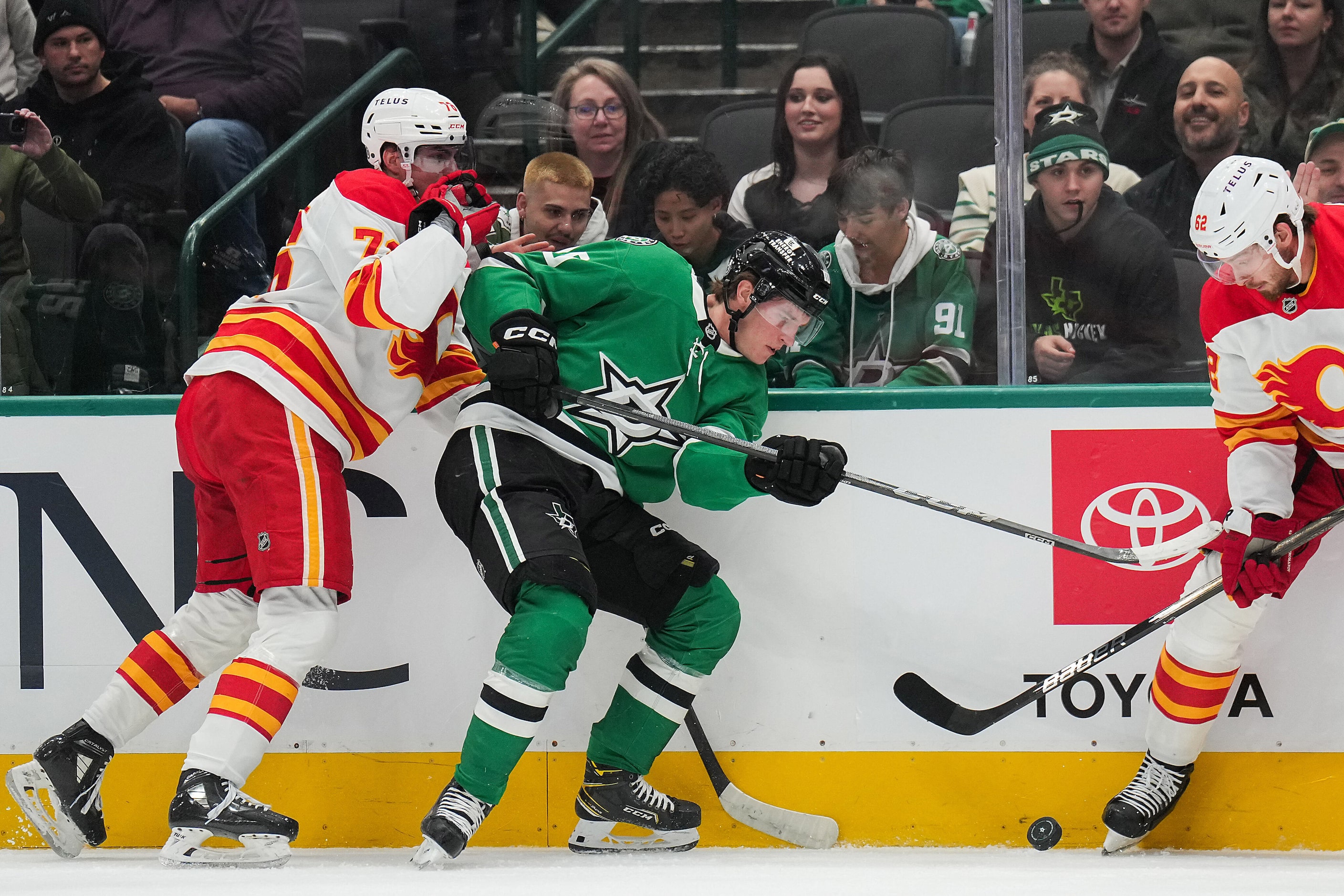 Dallas Stars center Oskar Bäck (10) fights for the puck along the boads with Calgary Flames...