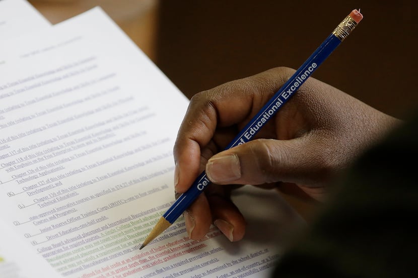 Texas Board of Education member Lawrence A. Allen Jr. uses a pencil to to mark and follow...