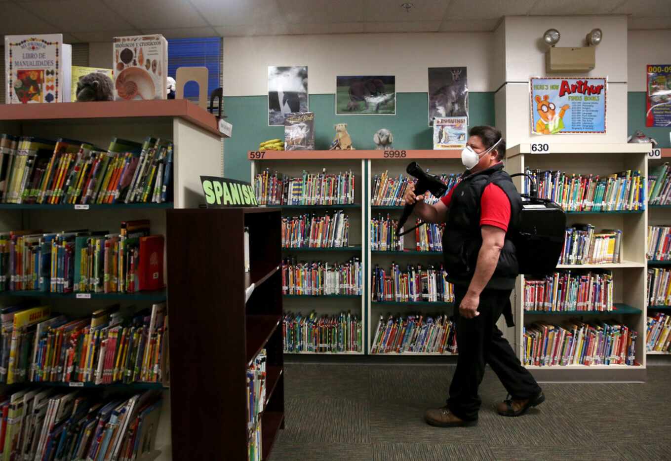 Julian Cruz, a custodian with Garland ISD, sprays a disinfectant in a classroom at Parkcrest...