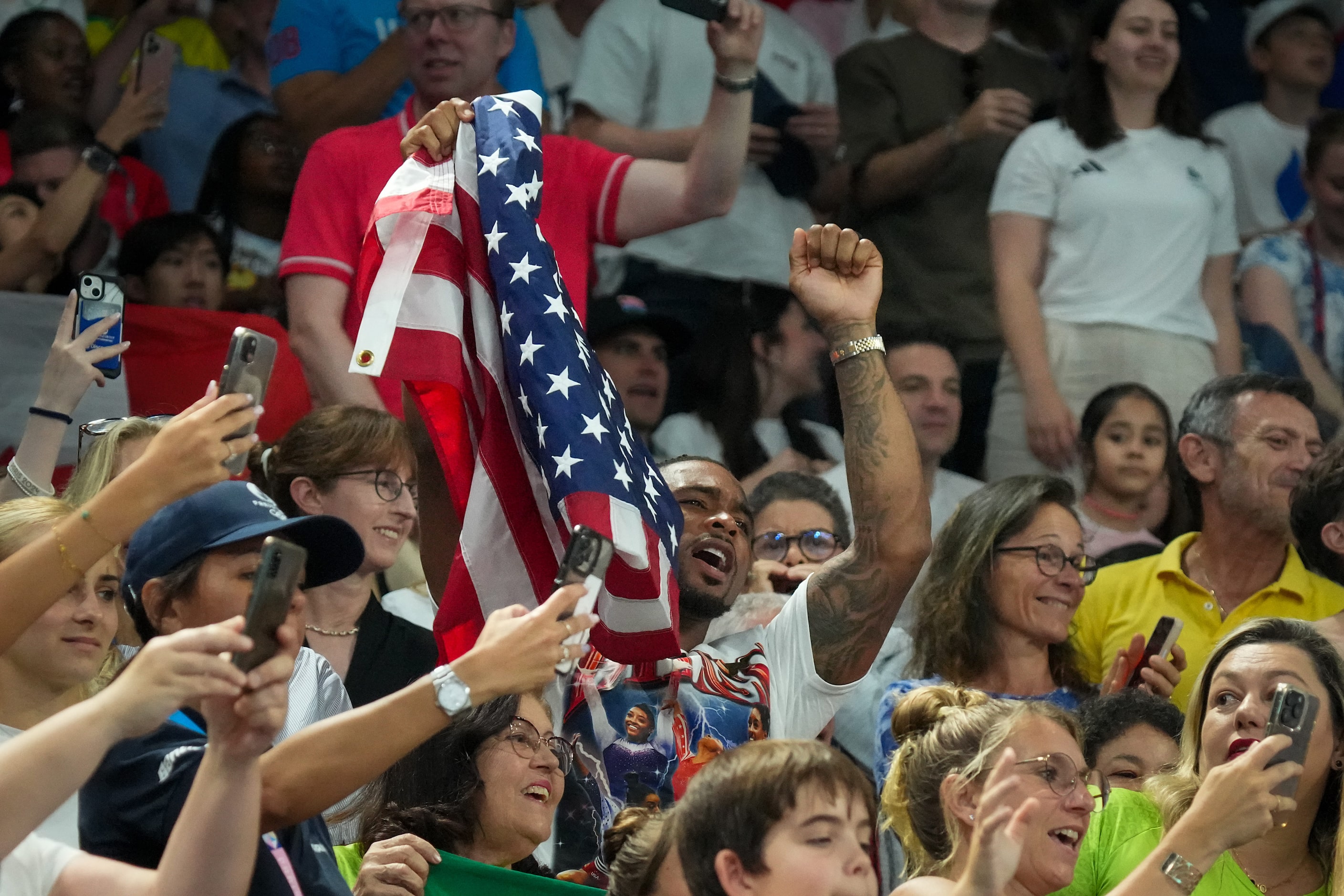 Simone Biles husband, Chicago Bears safety Jonathan Owens, waves a flag as he joins the...