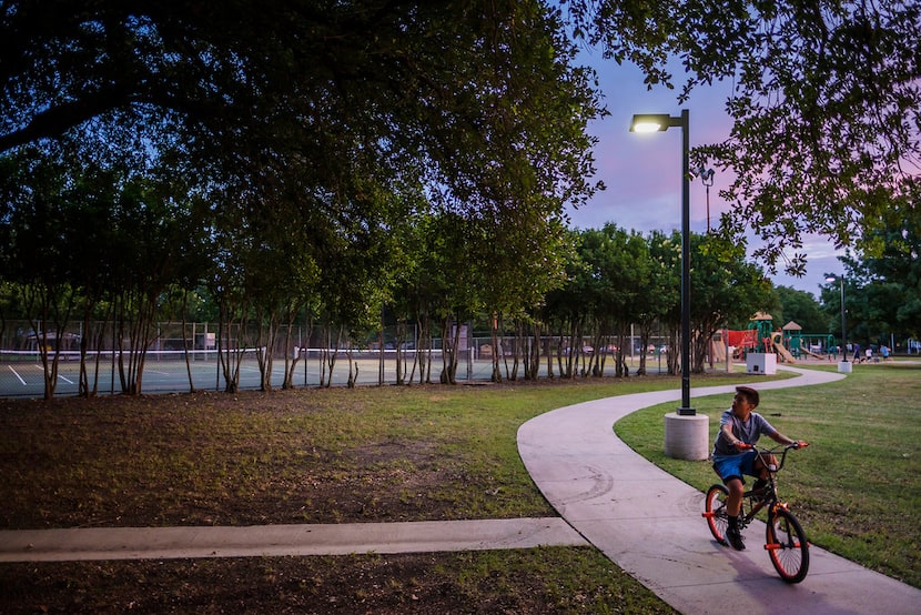 A youngster rides his bike Monday along the trail in Ferguson Park where three dogs attacked...