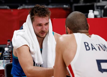 Slovenia’s Luka Doncic (77)  talks with France’s Nicolas Batum (5) as he sits dejected after...