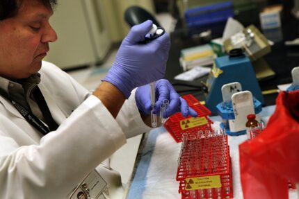 Harish Kothari, medical technician, uses a pipette to fill test tubes with serum and a...