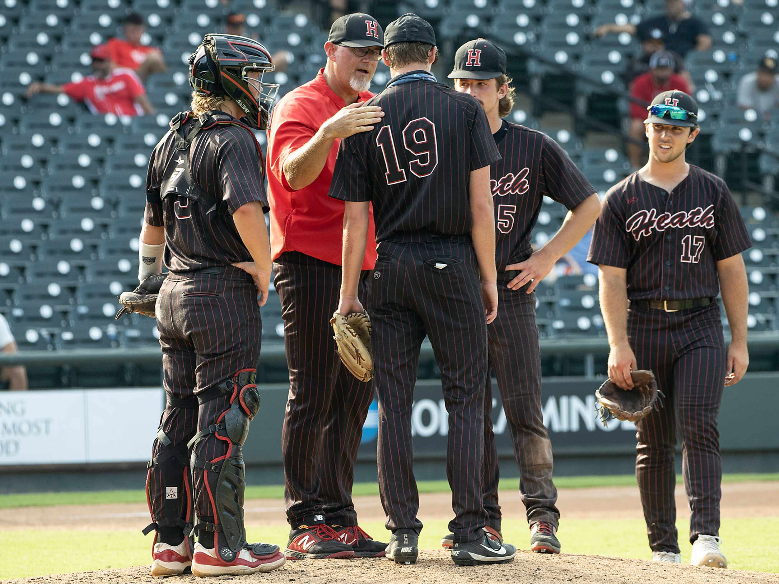 Rockwall-Heath head coach, Greg Harvey, pulls pitcher, Johnny Lowe, (19), and moves to...