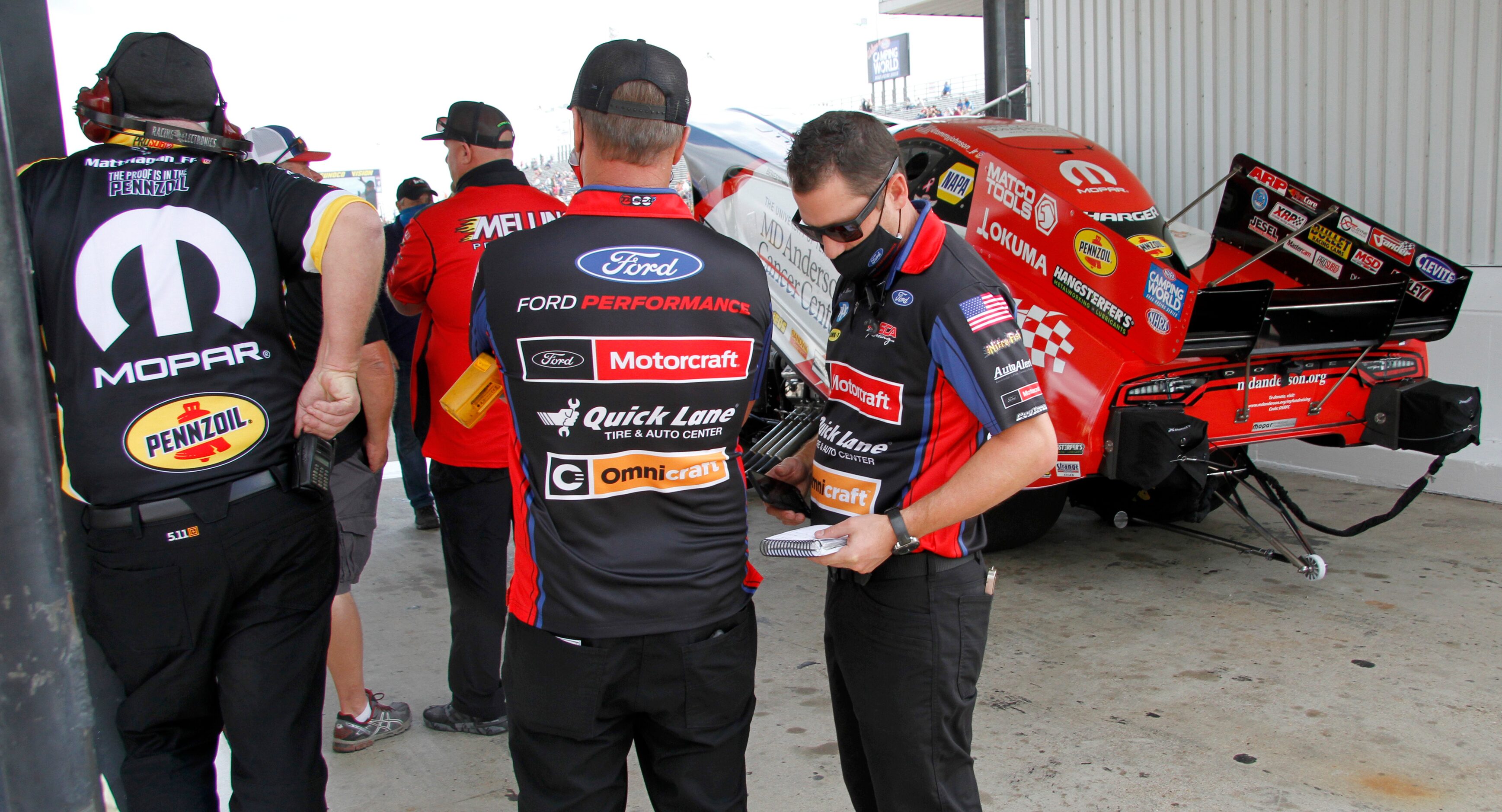 Members of a racing team pause as track officials work to clear the track following a crash....