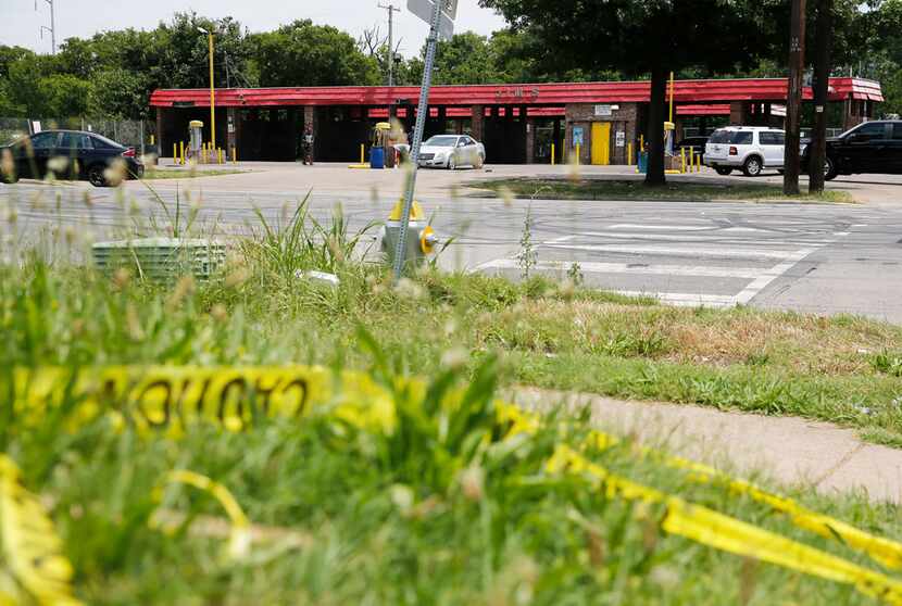 Caution tape on the ground across the street from Jim's Car Wash in Dallas on Monday. Four...