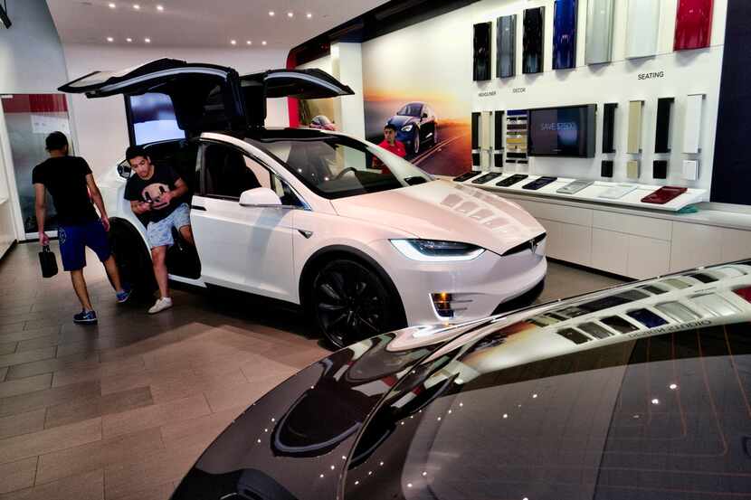 Customers check out the Tesla X, at the Tesla showroom in Santa Monica, Calif., on...