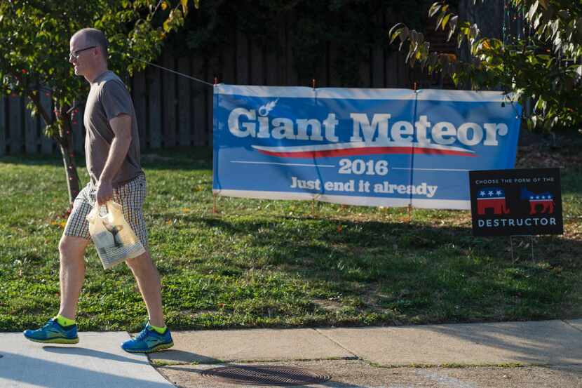 A man walks past parody election signs in the yard of James Hurd in Arlington, Va. Insults,...