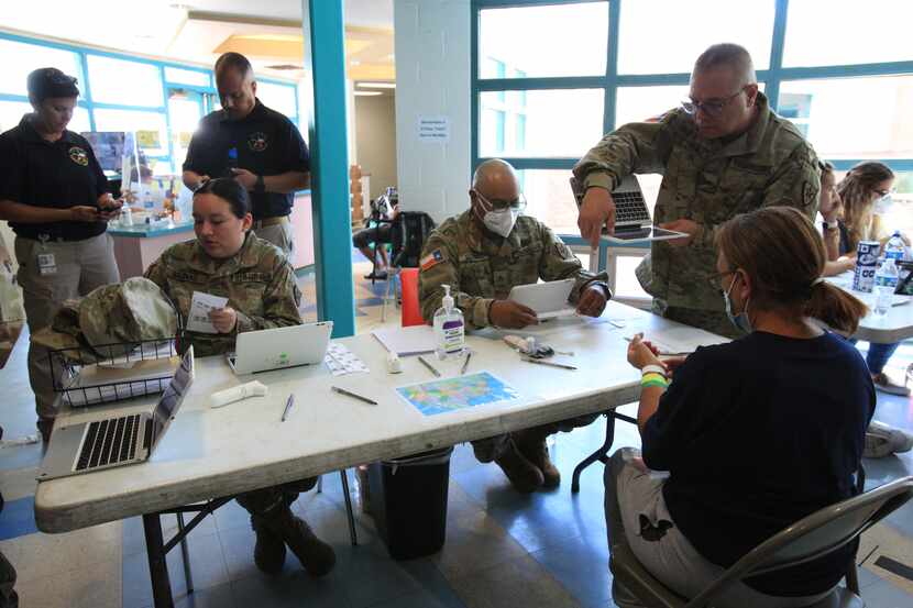 Texas National Guard agents at the Opportunity Center's Welcome Center assist in processing...